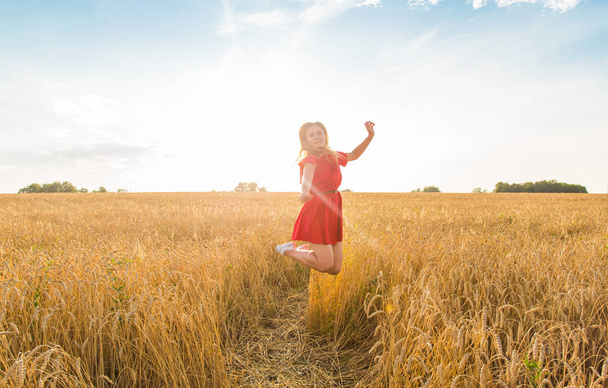 Happy woman jumping in golden wheat - Фото, изображение