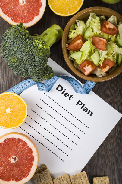 Food and sheet of paper with a diet plan on a dark wooden table. - Φωτογραφία, εικόνα