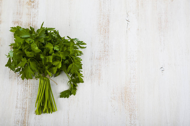 Fresh parsley on a light wooden background. - Фото, зображення