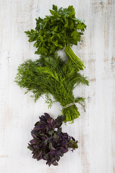 Parsley, dill and basil on a light wooden background. - Фото, изображение
