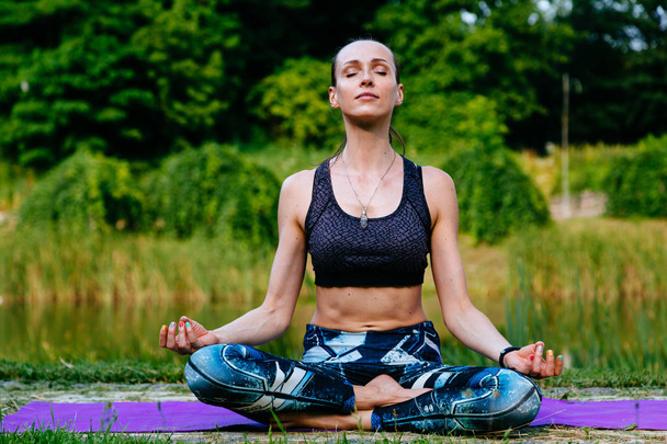 Mujer joven haciendo ejercicio de yoga en el parque verde. Imagen tonificada
. - Foto, imagen