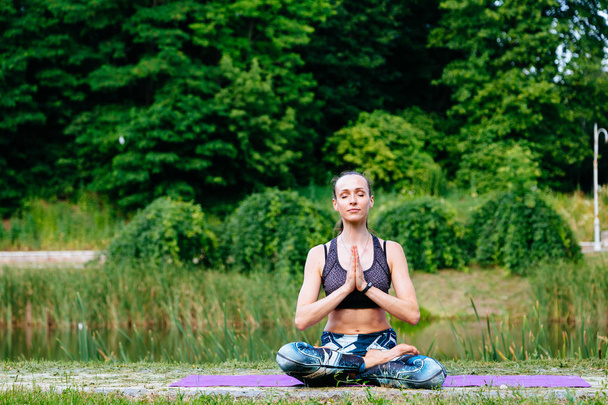 Mujer joven haciendo ejercicio de yoga en el parque verde. Imagen tonificada
. - Foto, imagen