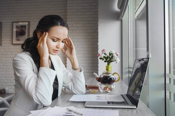 Awful headache makes woman suffer during working day. - Valokuva, kuva