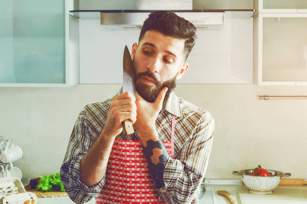 handsome man joking at kitchen with knife - Foto, afbeelding