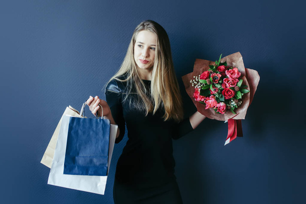 Cute girl with bouquet of red tulips and packages. - Foto, immagini