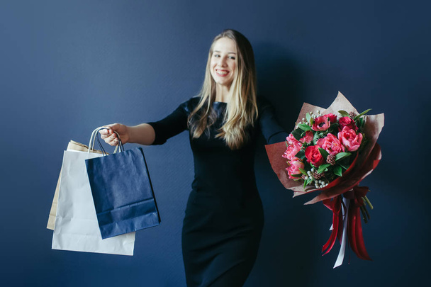 Cute girl with bouquet of red tulips and packages. - Valokuva, kuva