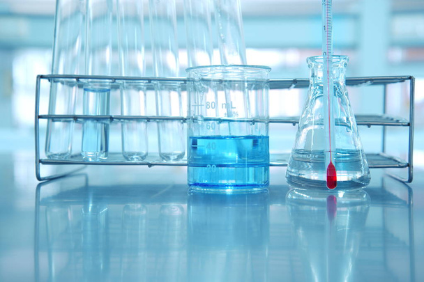vaso de precipitados y frasco con agua azul y termómetro en el laboratorio de ciencias
 - Foto, Imagen