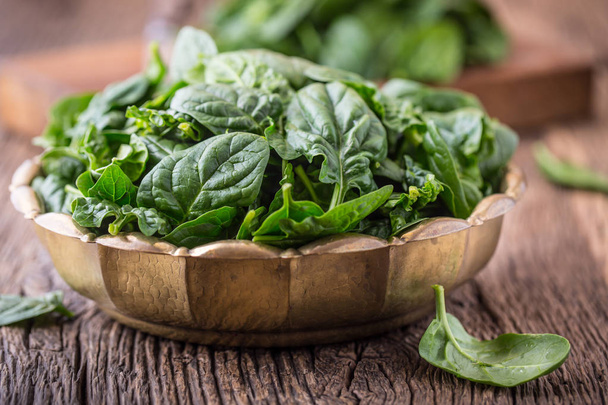 Spinach leaves.Fresh spinach leaves in retro bowl on oak wood board. Selective focus - 写真・画像