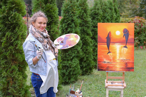 Künstlerin Frau hält Gemälde und betrachtet es, posiert vor der Kamera ein - Foto, Bild
