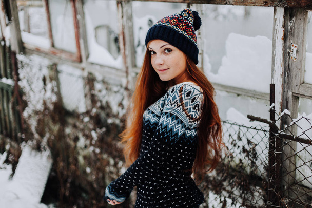 Retrato de hermosa niña pecosa con el pelo rojo largo y lindo encantadora sonrisa vistiendo sombrero elegante gris mirando y sonriendo al pie de la cámara sobre fondo de pared de estudio. Aislado plano, horizontal - Foto, imagen