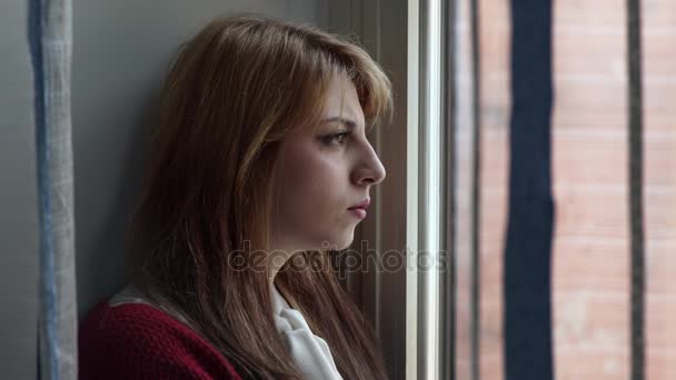 Προφίλ της ξανθιάς γυναίκας, λυπημένος και στοχαστικό στο παράθυρο - Πλάνα, βίντεο