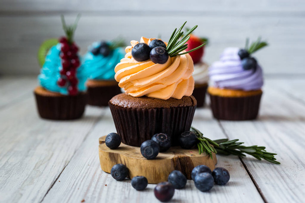 Σοκολάτα cupcakes. Cupcakes. Cupcakes με μούρα, φρούτα, φράουλες. Top view.colorful cupcake, νόστιμα κέικ, πολύχρωμο κρέμα, cupcakes με μούρα σε ξύλινο υπόβαθρο, εσωτερικη, επιδόρπιο έννοια - Φωτογραφία, εικόνα