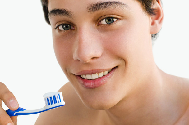 Handsome young man smiling and holding a toothbrush - Fotó, kép