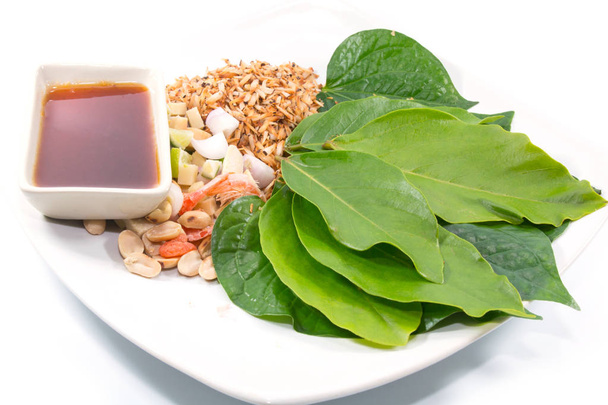 Miang Kham is a tasty snack often sold as Thailand street food. It involves wrapping little tidbits of several items in a leaf, along with a sweet-and-salty sauce. - Photo, Image