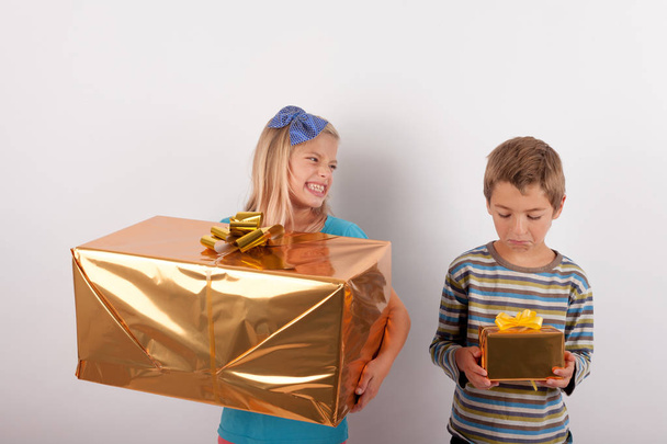 Young girl with big gift box gloating over her brother and his s - Фото, изображение