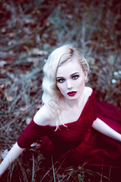 Divat gyönyörű fiatal szőke nő egy mesebeli erdő gyönyörű piros ruha. a varázslatos hangulatot. Retusált alakformálás lövés - Fotó, kép