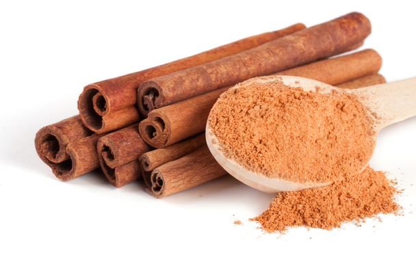 a stack of cinnamon sticks and powder with spoon isolated on white background - Photo, Image