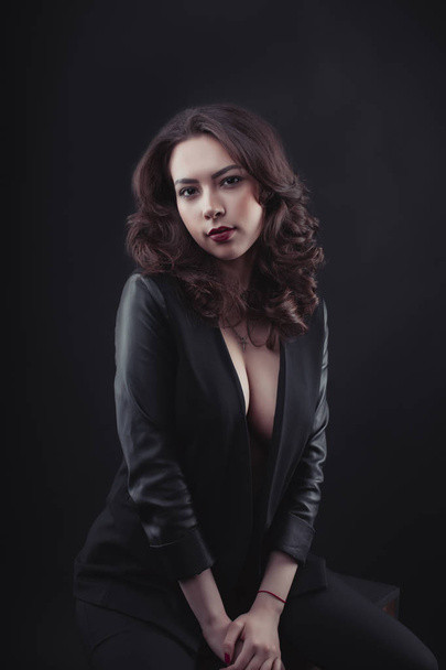 Model with decollete and leather jacket in the shadows - Photo, Image