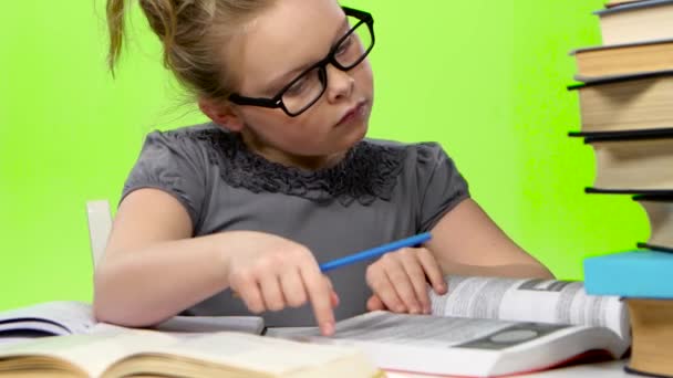 Little girl in glasses looking in books information. Green screen - Video, Çekim