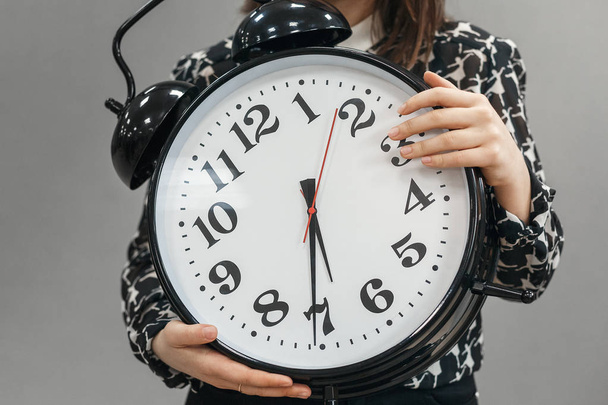 The girl holding a very large alarm clock - Zdjęcie, obraz