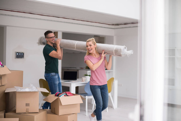 couple carrying a carpet moving in to new home - Foto, imagen