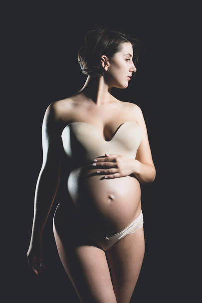 pretty pregnant woman with round belly isolated on black - Фото, изображение