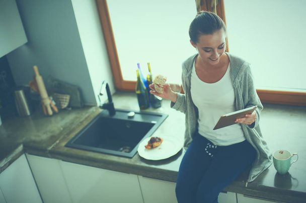 Beautiful young woman using a digital tablet in the kitchen - Φωτογραφία, εικόνα