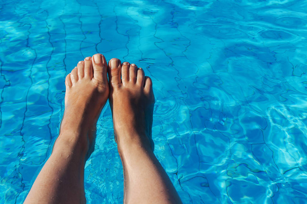piernas femeninas desnudas sobre un fondo de agua azul
 - Foto, imagen