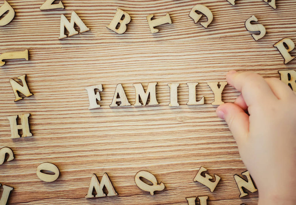 το παιδί συλλέγει τις σημαντικές λέξεις από τα ξύλινα γράμματα. επιλεκτική εστίαση.  - Φωτογραφία, εικόνα
