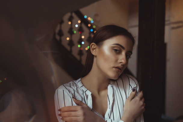 Glamorous young brunette lady with garlands on background - Valokuva, kuva