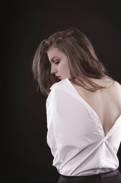 Seductive young woman in shirt with naked back at studio - Foto, imagen