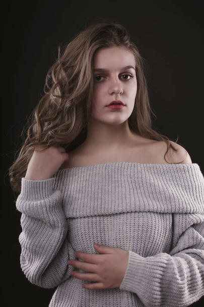 Fabulous young woman posing in sweater with naked shoulders - Фото, изображение