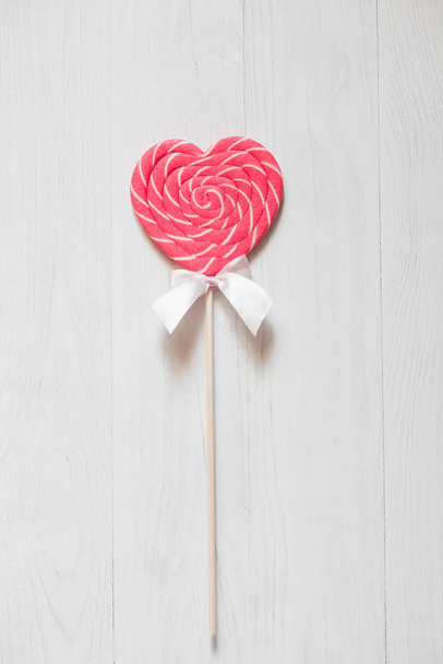 Sweet candies in heart shape on white wooden background - 写真・画像