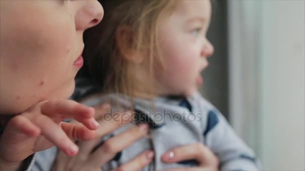 Mom with little girl looking through the window - Кадри, відео