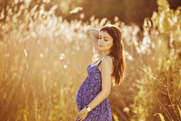 Beautiful tender pregnant woman smiles and enjoys a sunny summer - Fotografie, Obrázek