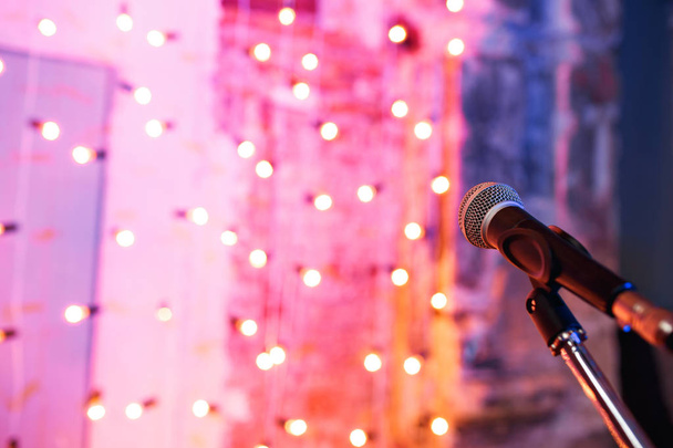 Nahaufnahme des Mikrofons im Konzertsaal mit verschwommenem Licht im Hintergrund - Foto, Bild