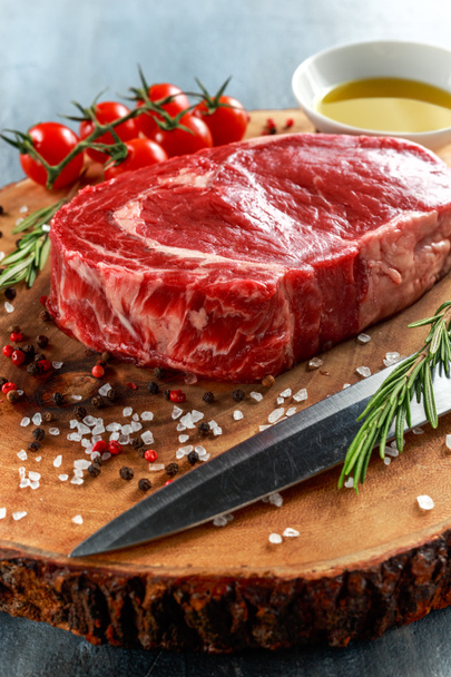 Fresh Raw Beef Steak Ribeye, with salt, peppercorns, rosemary, tomatoes and olive oil - Photo, Image