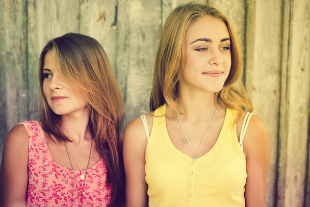 Δύο ευτυχισμένη θηλυκό φίλους χαμογελώντας πάνω από χλωμό φόντο ξύλινη - Φωτογραφία, εικόνα