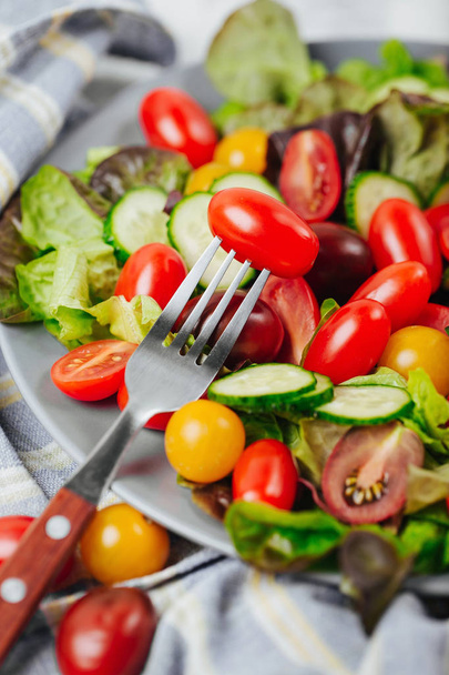 Tomato on a fork close up. Healthy salad of red and yellow cherry tomato and herbs. - Foto, Imagem