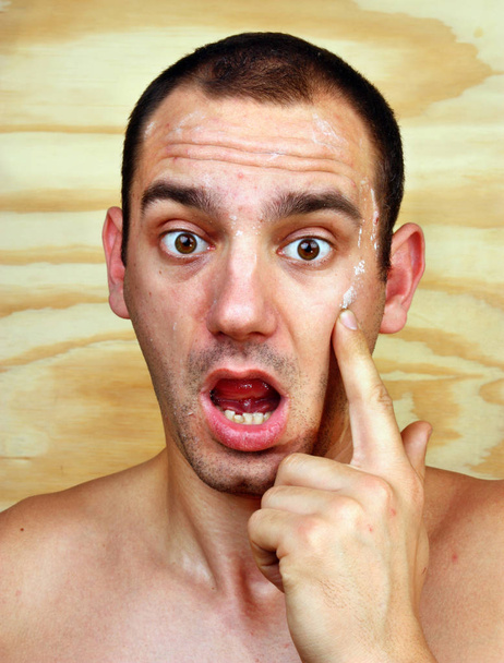De jonge man in verrassing op het gezicht van infecties van de huid - Foto, afbeelding