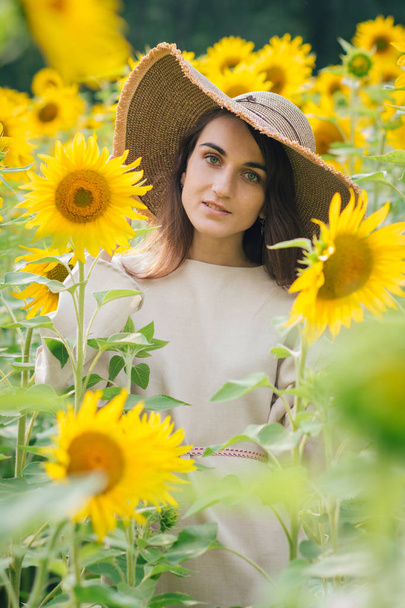 Young girl in a hat on a field of sunflowers - Фото, зображення