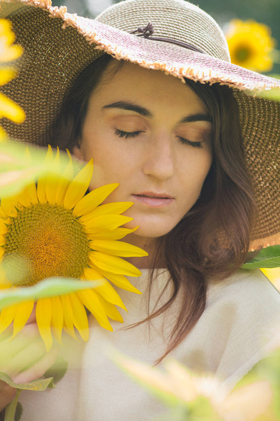 Young girl in a hat on a field of sunflowers - Fotografie, Obrázek