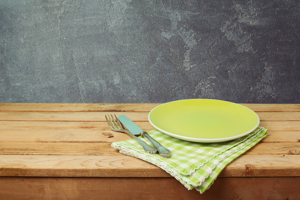 Green plate on wooden table  - Фото, зображення