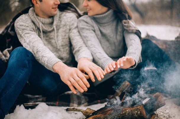 Молода жінка і чоловік розігрівають руки над багаттям взимку
 - Фото, зображення