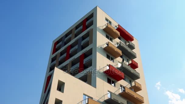 La parte superior de un edificio de apartamentos de colores en una zona urbana, el cielo azul con escasas nubes blancas en el fondo
 - Imágenes, Vídeo