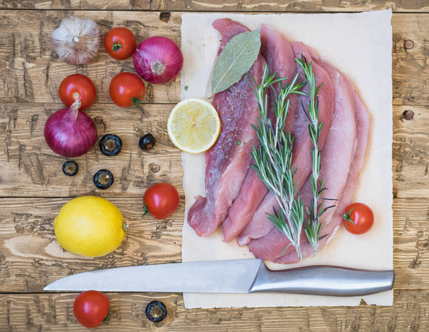 Roh geschnittenes Schweinefleisch mit Gewürzen und Gemüse auf einem rustikalen Tisch. - Foto, Bild