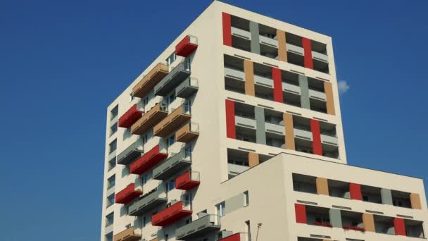 La parte superior de un edificio de apartamentos de colores en una zona urbana, el cielo azul en el fondo
 - Imágenes, Vídeo