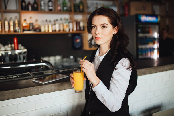 Young woman holding glass of fresh orange juice at restaurant bar. Health trend. - Valokuva, kuva