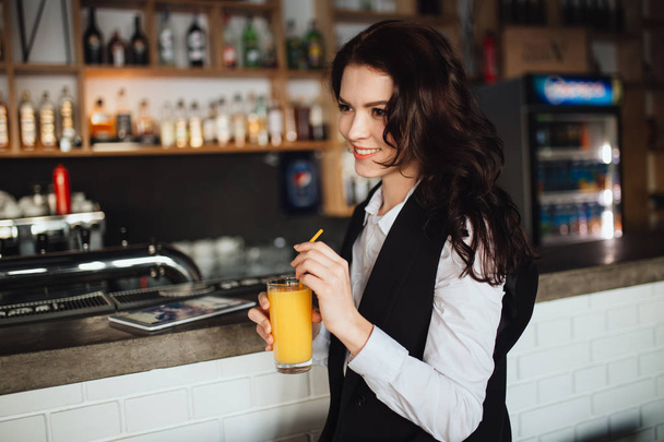 Beautiful woman holding glass of fresh orange juice at restaurant bar. Health trend. - Valokuva, kuva