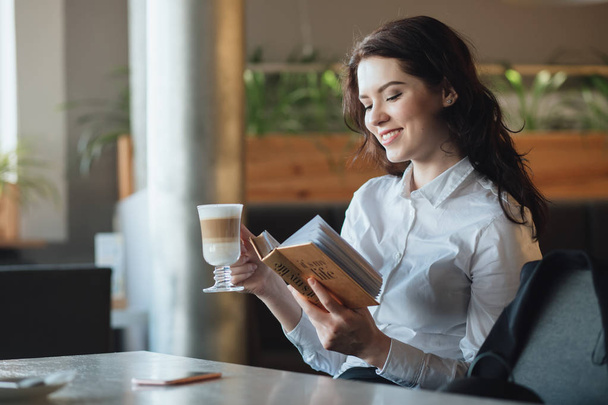 Young woman relaxing in cafe, drinking latte, reading diary book - Foto, Imagem